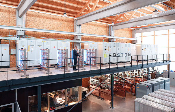 Interior view of the Energy Lab with technical infrastructure, test facilities and a person walking on an elevated platform.