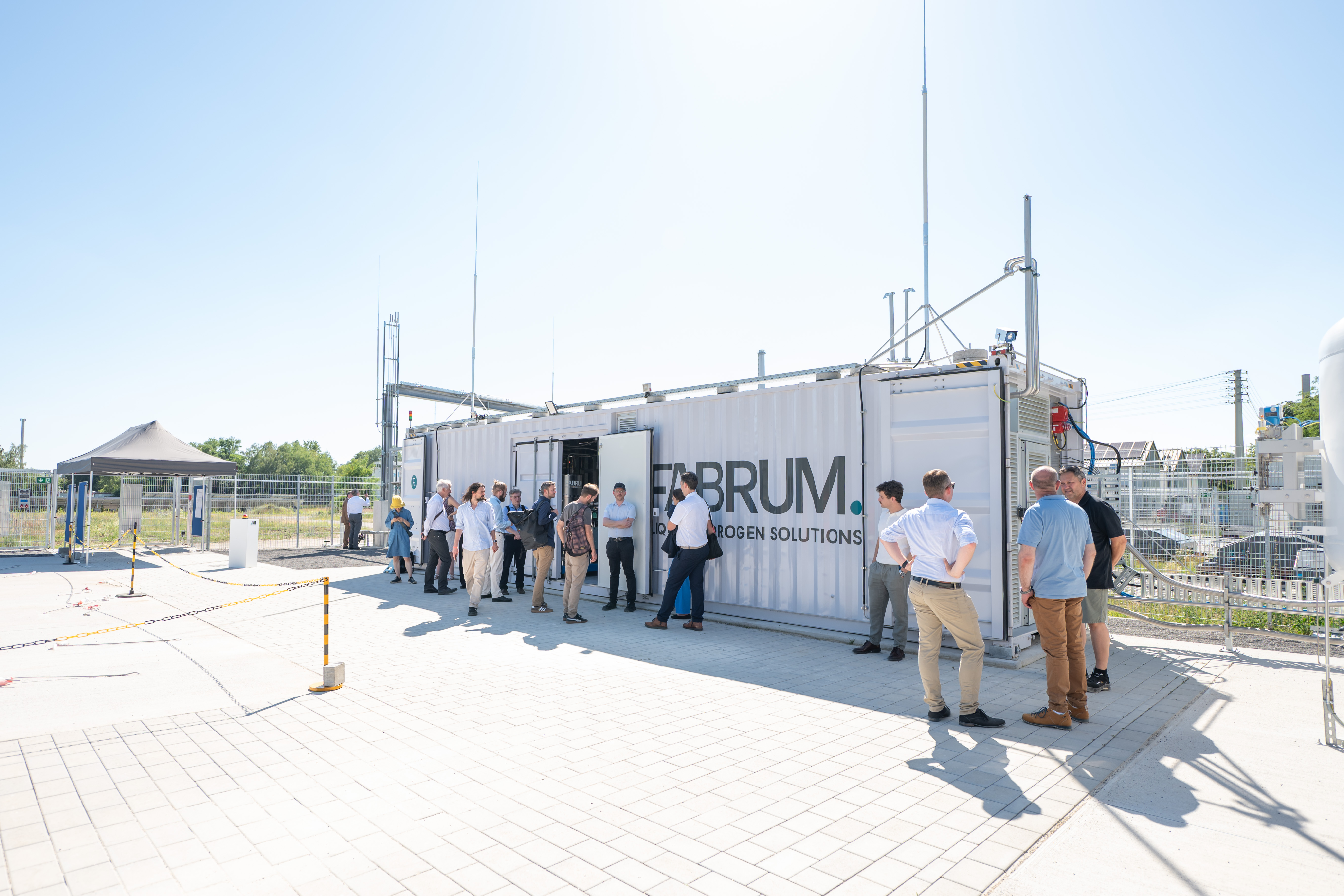 Gruppe von Fachleuten vor einem technischen Container-Modul der Firma Fabrum unter freiem Himmel.